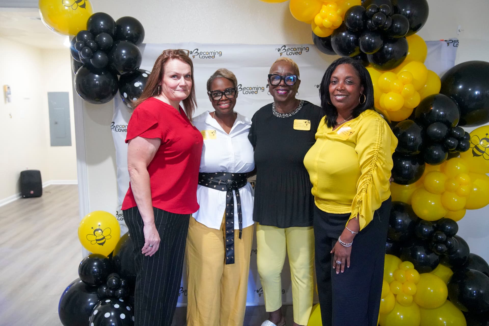 Four attendees gathered beside black and yellow balloons at the celebration